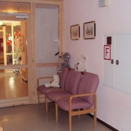 Eine Krankenschwester lächelt einen älteren Patienten im Zimmer an.