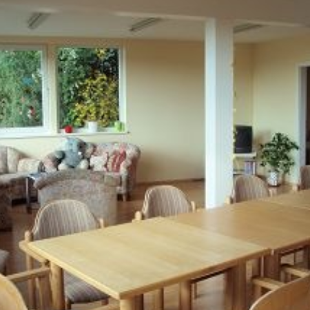 Eine Pflegekraft hilft einem älteren Ehepaar beim Ausmalen.