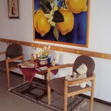 Eine Pflegekraft unterstützt ältere Frauen beim Stricken.