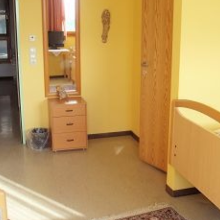 Eine Pflegekraft unterstützt ältere Frauen beim Stricken.