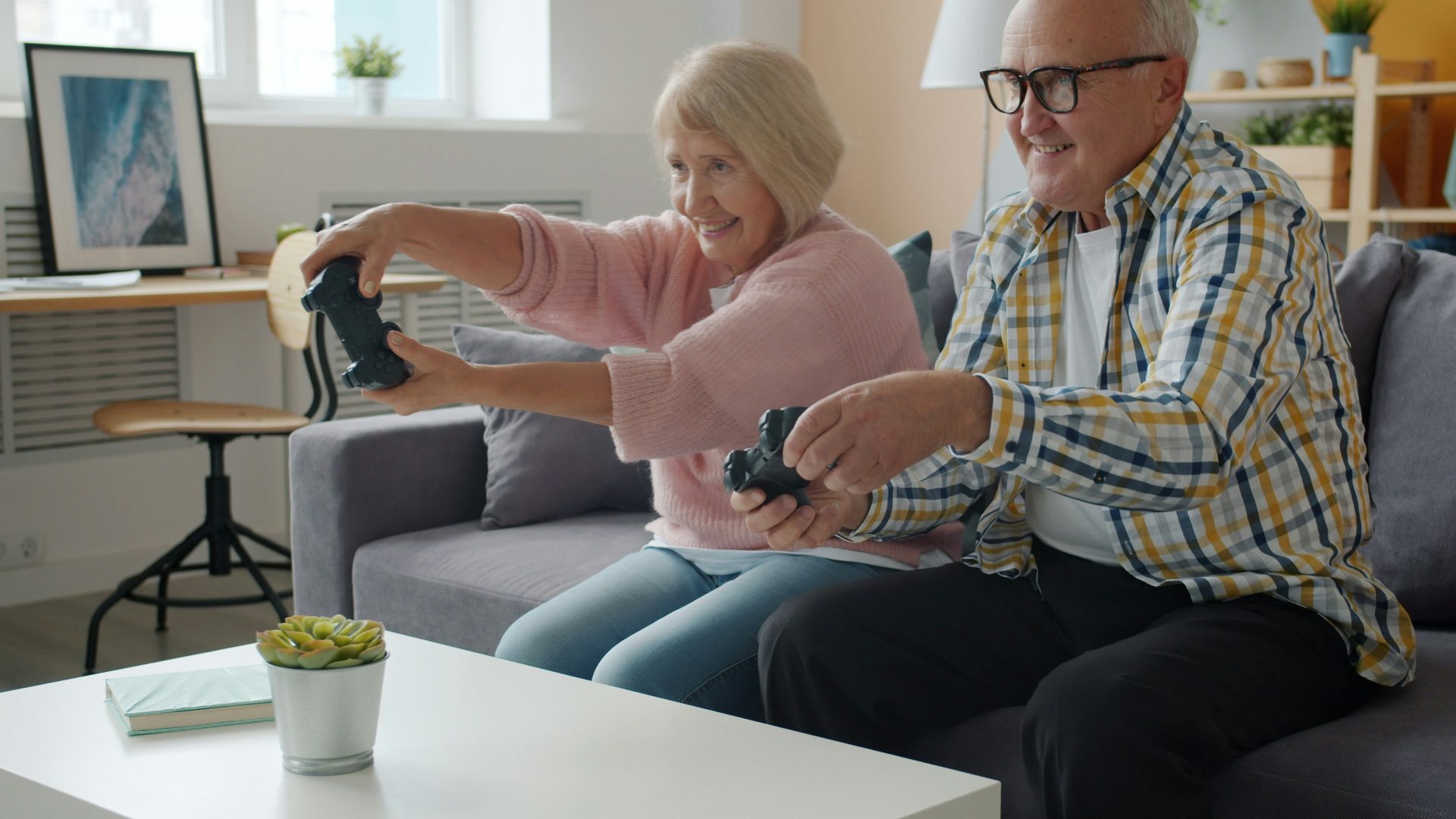 Elderly couple playing video games together on couch